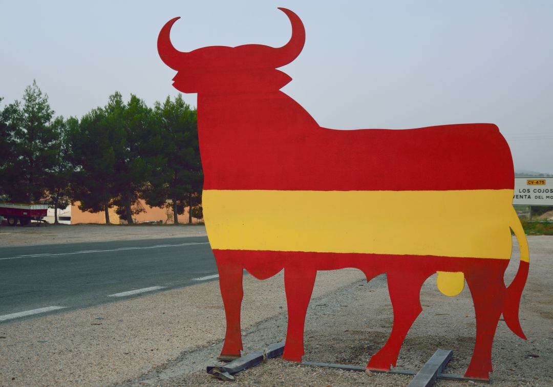 Toro típico español pintado con la bandera de España en una carretera