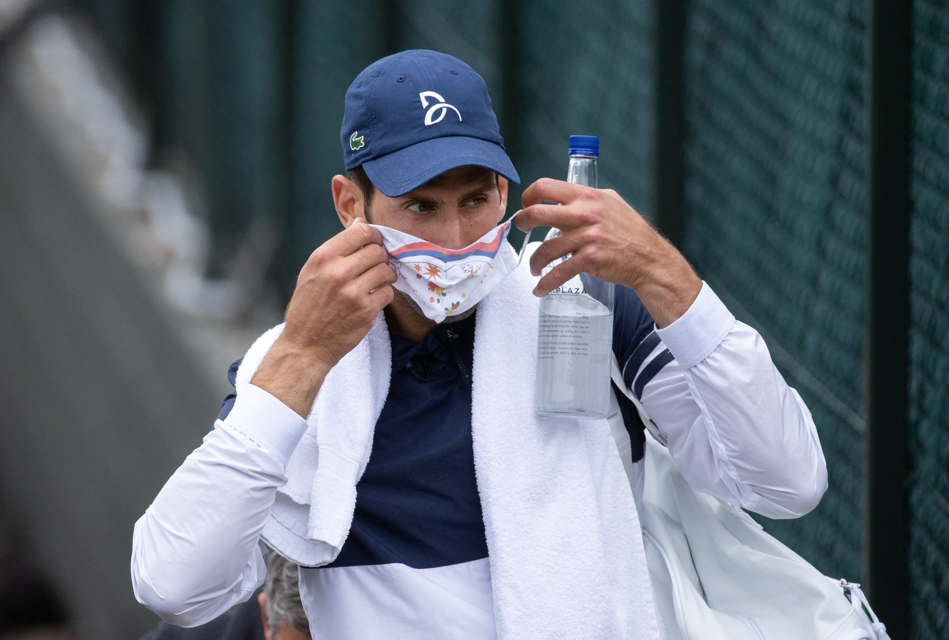 Novak Djokovic se coloca la mascarilla en 2021 antes de entrenar en Wimbledon (Photo by AELTC/David Gray / POOL / AFP) / RESTRICTED TO EDITORIAL USE (Photo by AELTC/DAVID GRAY/POOL/AFP via Getty Images)