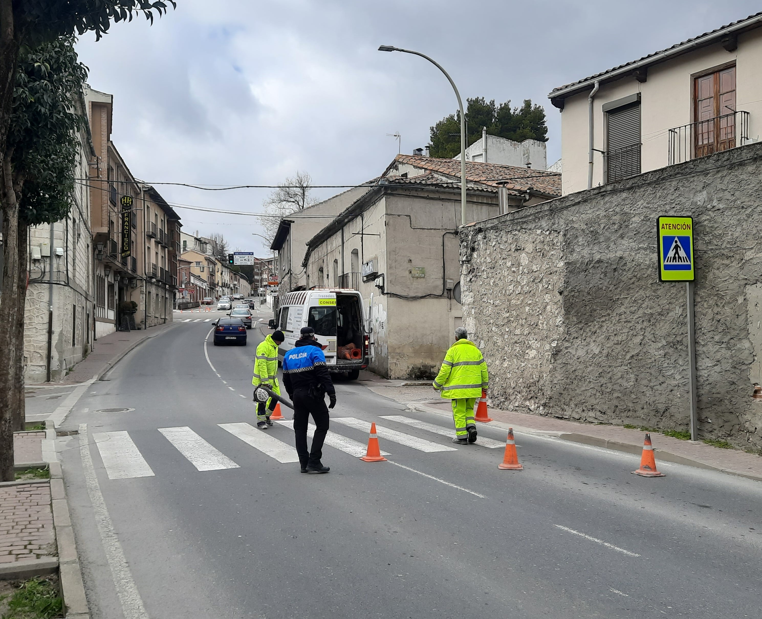 Un policía local ayuda en la regulación del tráfico durante los trabajos de repintado de un paso de peatones en Cuéllar