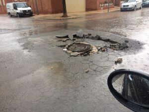 Una alcantarilla y el asfaltado dañado