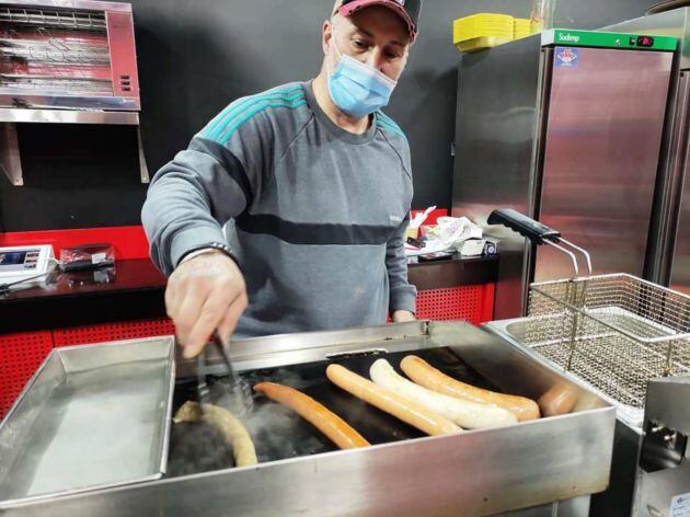 Kiko Rodríguez, delante de la plancha y el recipiente donde previamente cuece las salchichas