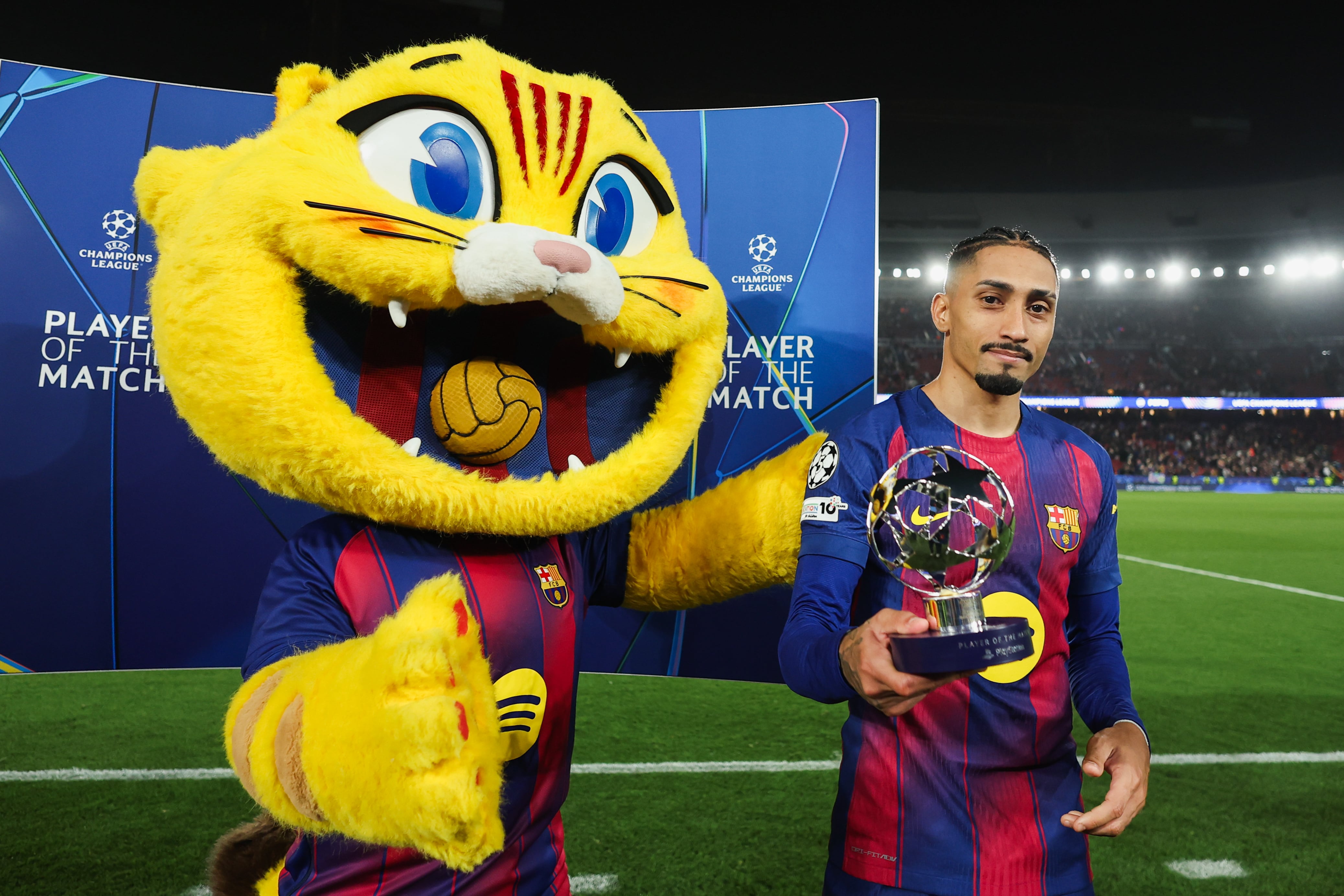Cat, la mascota del FC Barcelona, junto a Raphinha después de jugar ante el Newcastle