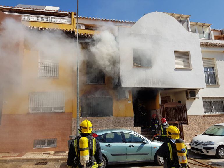 Los bomberos sofocando las llamas en la vivienda afectada en Málaga