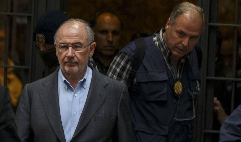 Rodrigo Rato es conducido al coche policial tras su detención.