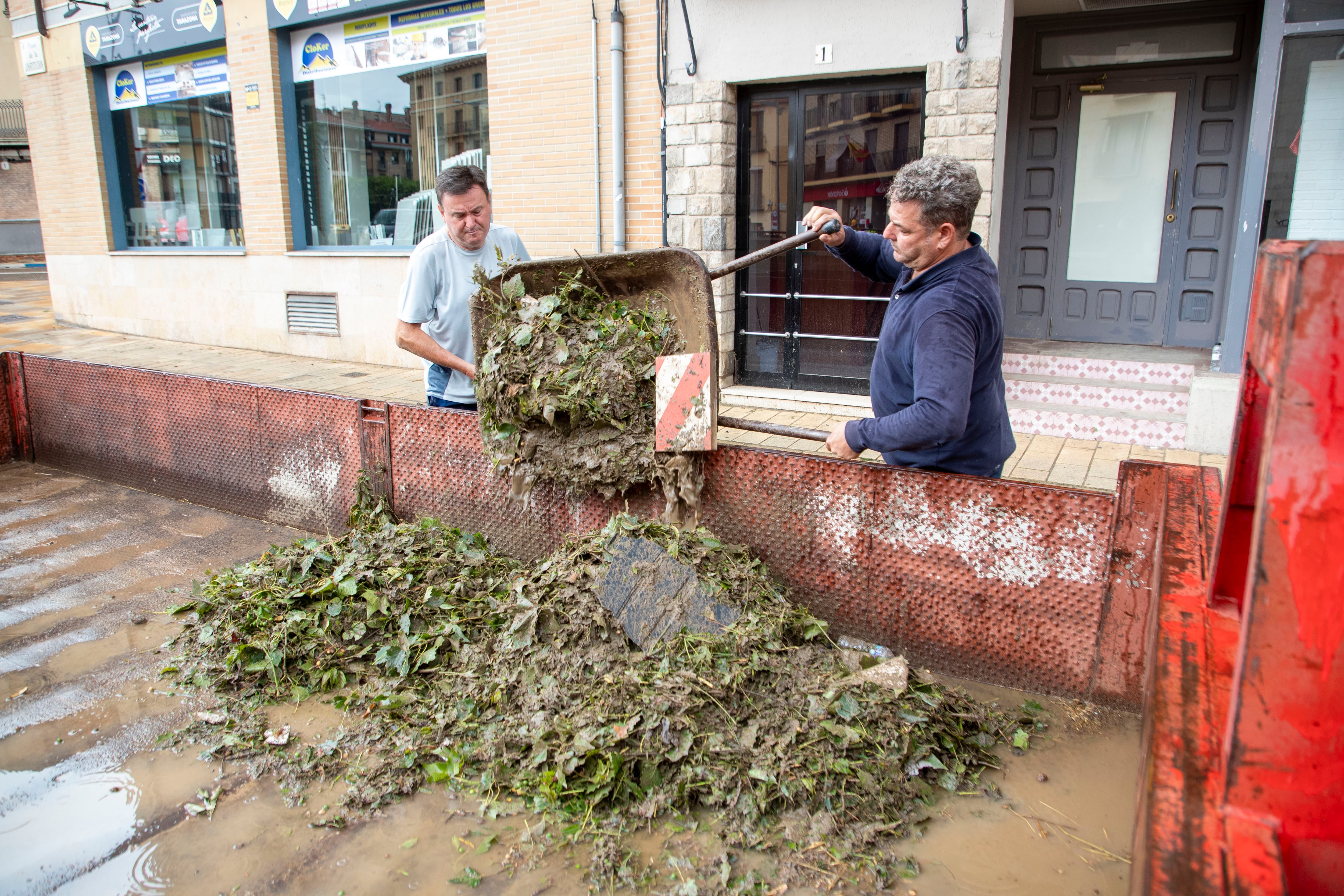 TARAZONA (ZARAGOZA), 12/07/2025.- Varias personas tras retirar las hojas que obstruyen los desagües y alcantarillas de los garajes inundados tras las últimas lluvias caídas en Tarazona. Aragón continúa en situación de alerta tras las intensas tormentas registradas esta semana, especialmente en las localidades zaragozanas de Tarazona, Pedrola y Grisén, donde sus vecinos vieron inundadas sus calles, garajes, locales y viviendas a causa de unas precipitaciones que descargaron hasta 100 litros por metro cuadrado en una hora. EFE/ Javier Belver
