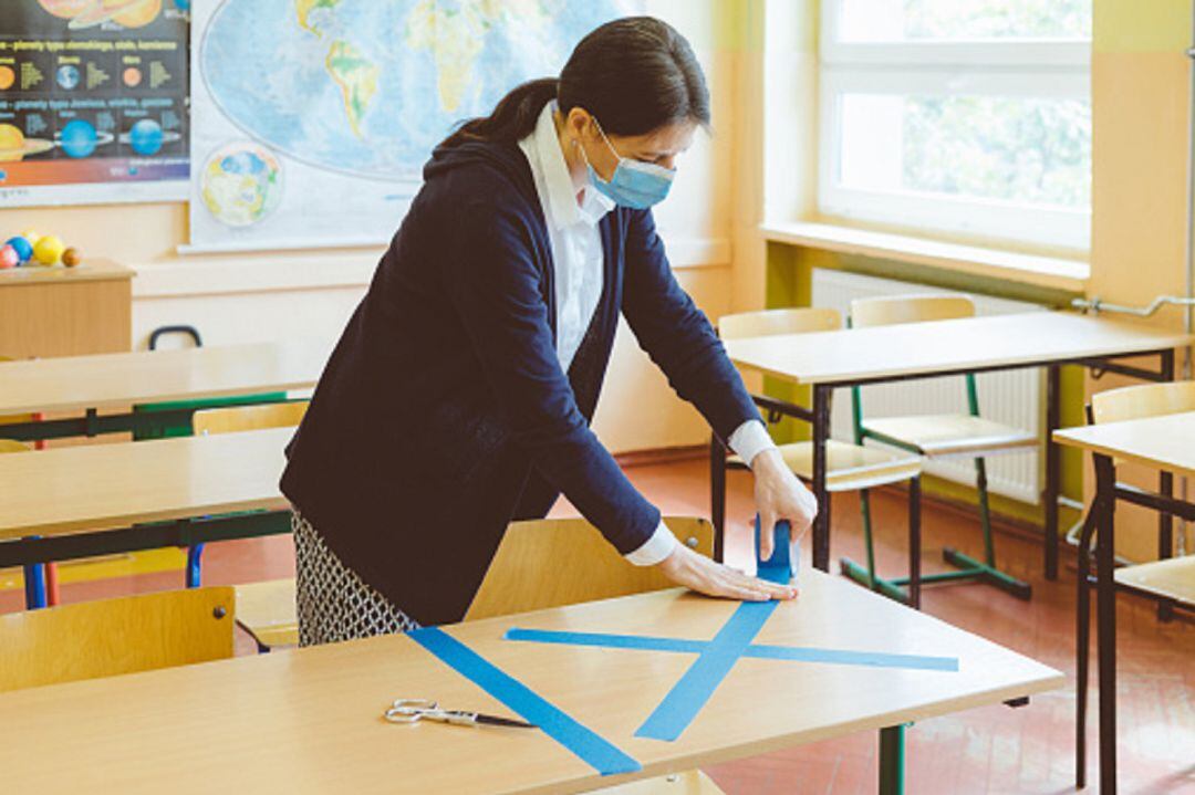 Maestra marcando medidas de seguridad en un aula