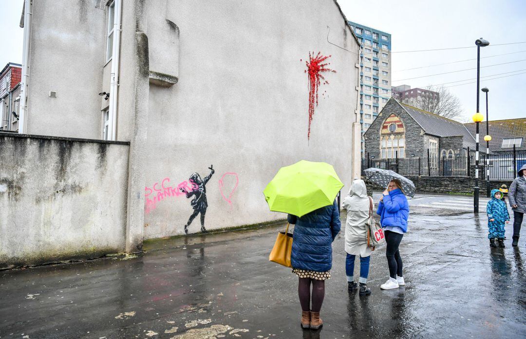 Un grupo de personas se paran frente a la última obra de Bunksy en Bristol, que amaneció el sábado tapada por una pintada vandálica.