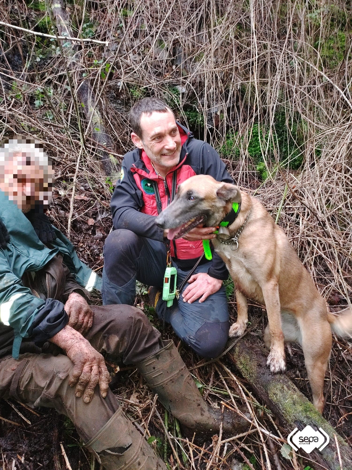 Imagen cedida por el Servicio de Emergencias del hombre desaparecido (con el rosto pixelado) junto a un rescatador y un perro de rastreo.