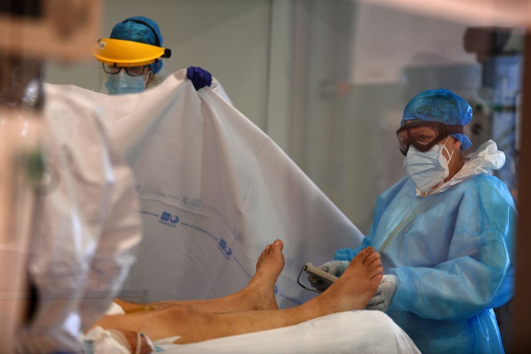 Personal sanitario atendiendo a un paciente de COVID-19 en la UCI. 