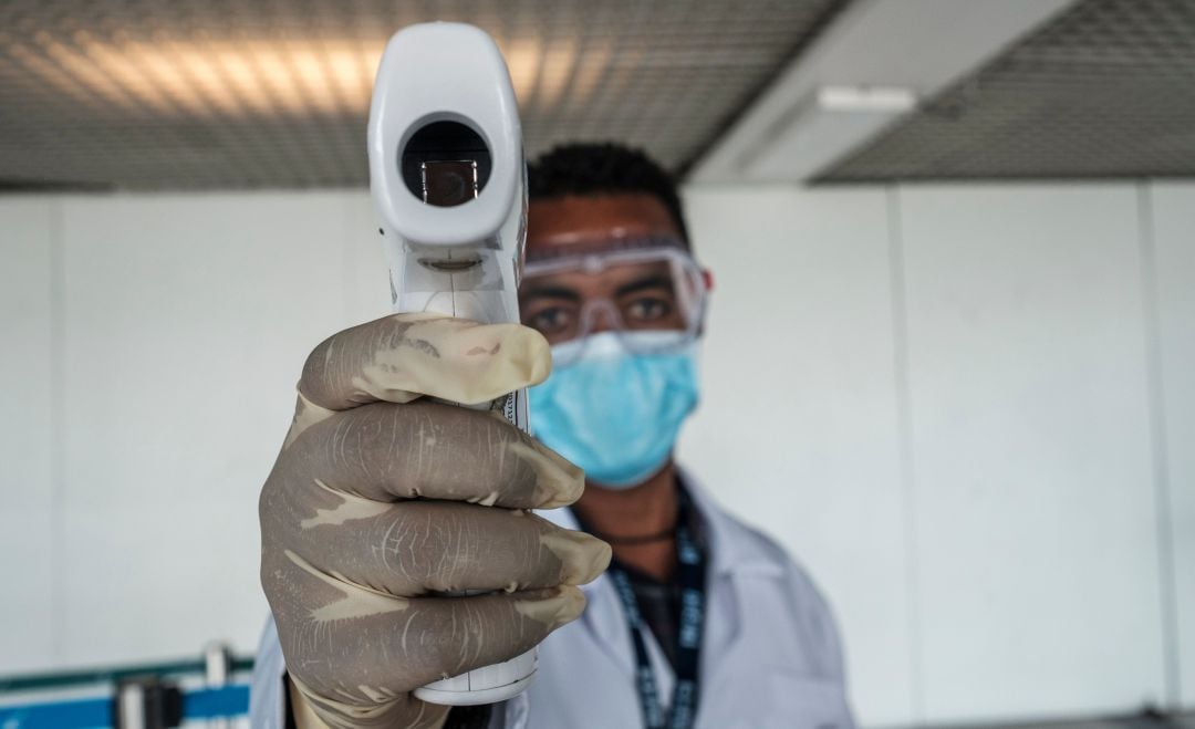 Un sanitario africano con un termómetro.