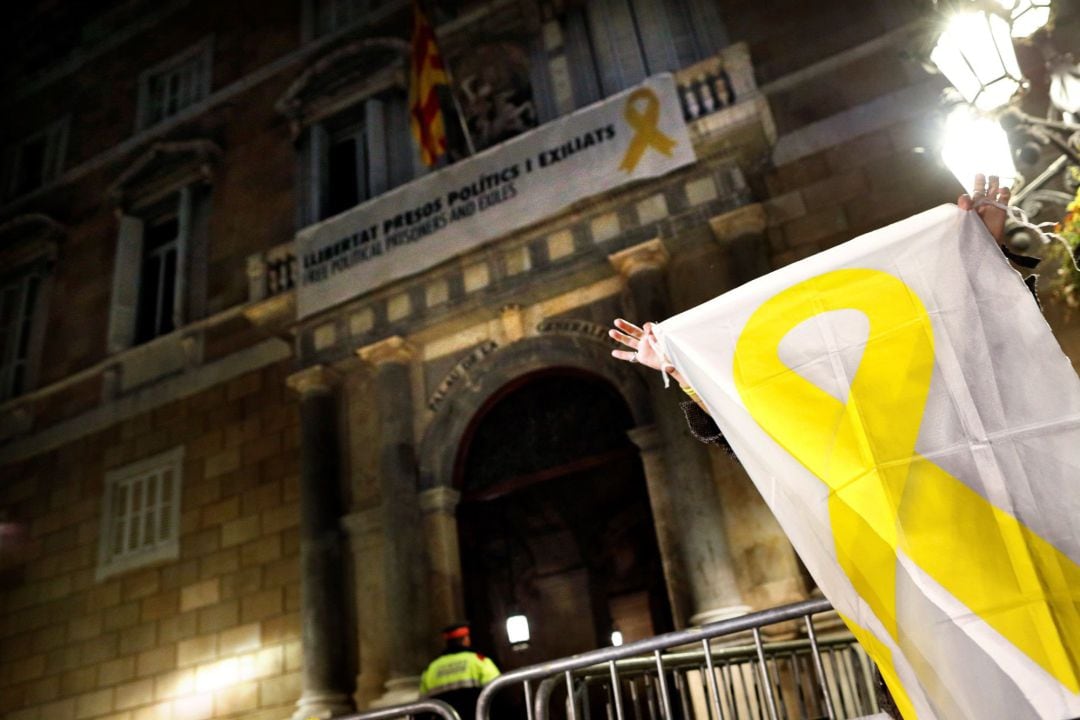 Una mujer muestra una pancarta con una lazo amarillo ante el Palau.