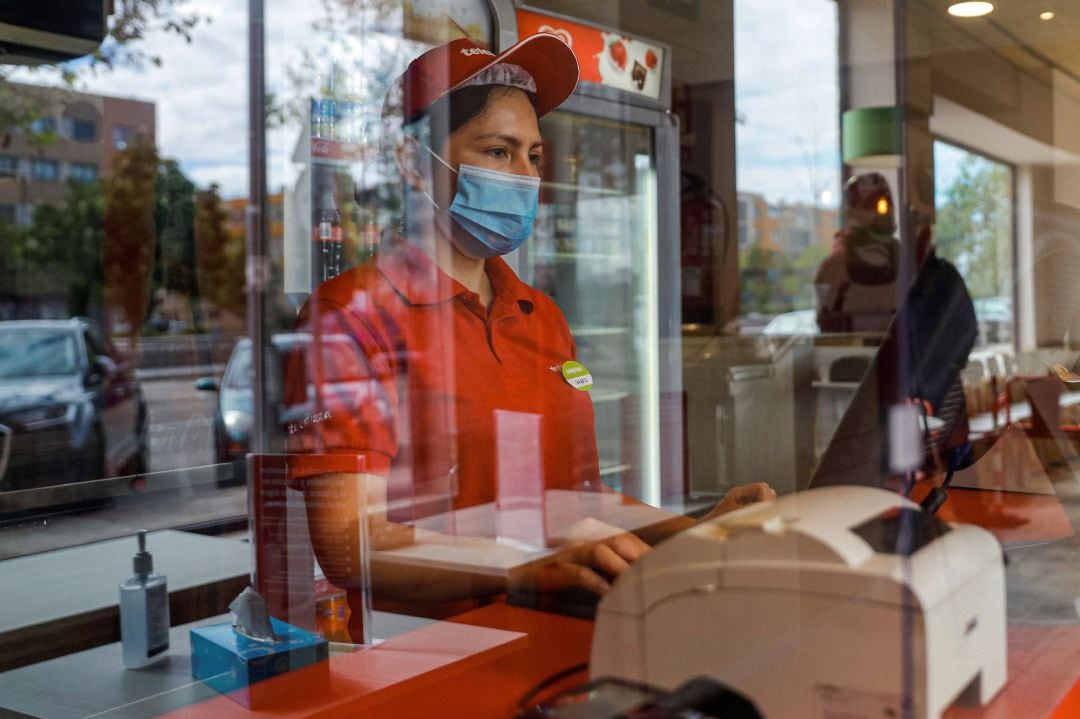 Una empleada de la cadena de pizzerias trabaja tras una mampara de protección