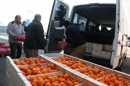 Voluntaris del Banc dels Aliments carregant una furgoneta d'una entitat benèfica que s'endú mandarines per a les famílies que necessiten ajuda per menjar.