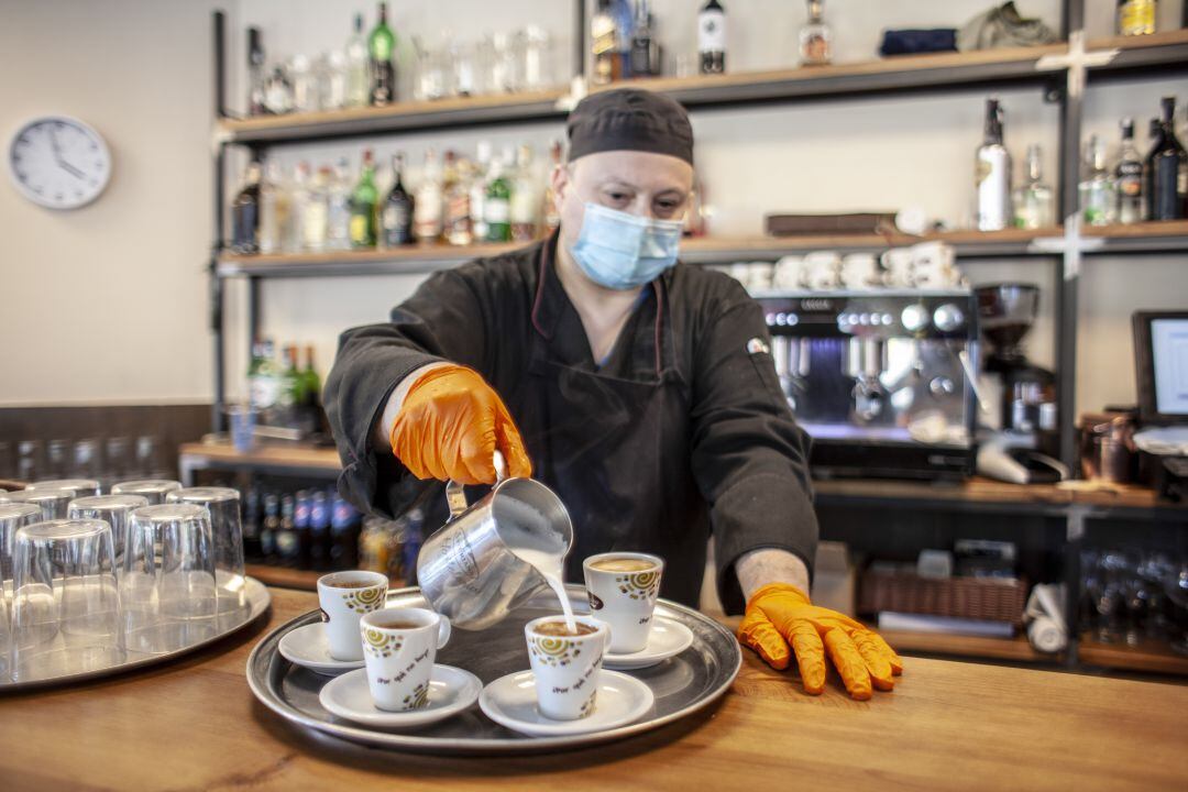 Camarero prepara cafés en un local de hostelería durante la pandemia por covid-19