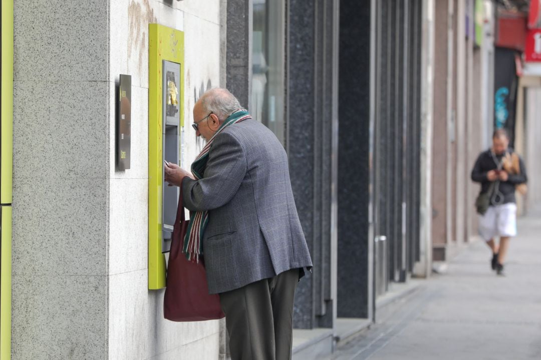 Persona mayor sacando dinero del cajero (foto de archivo)