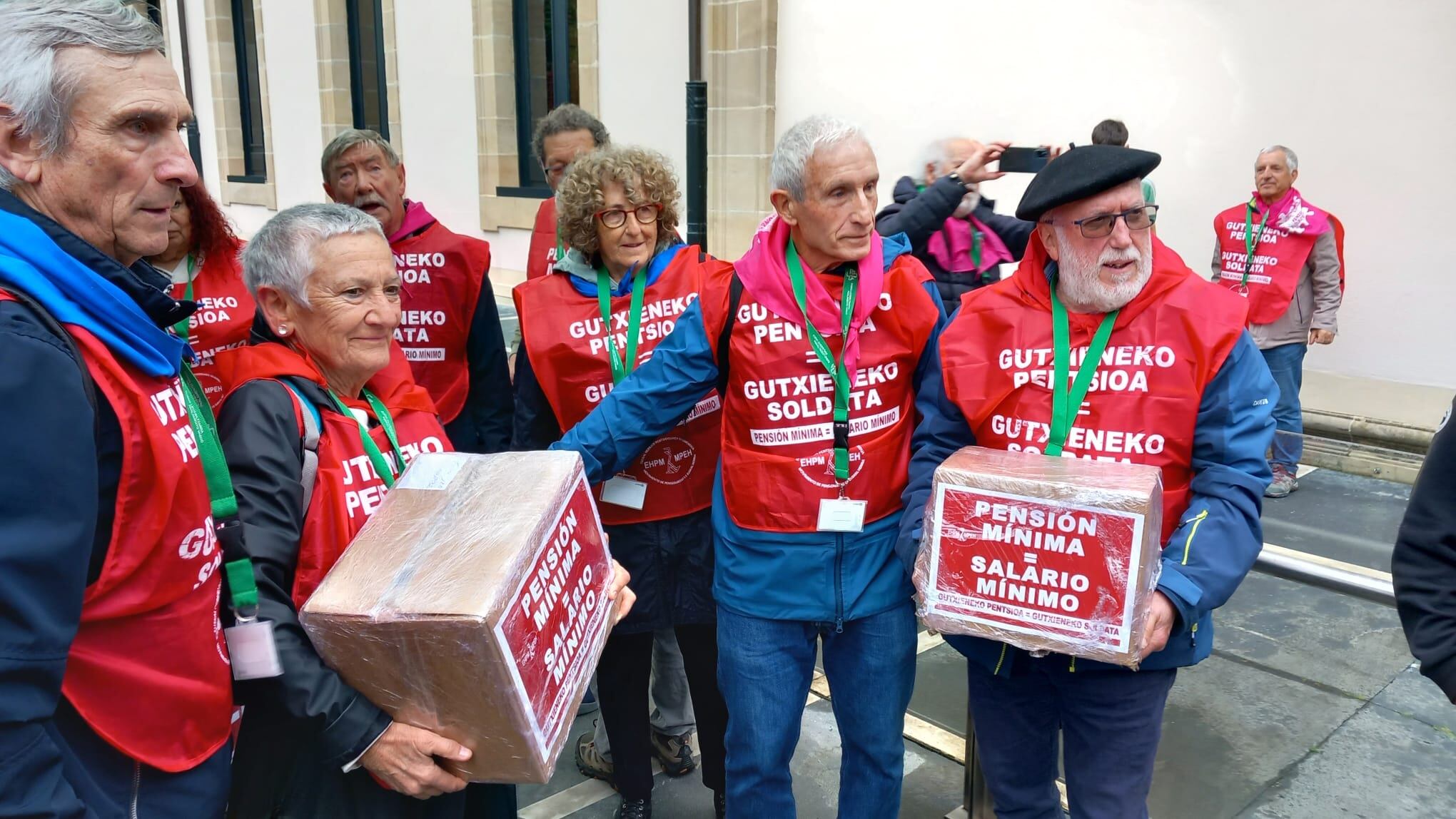 Representantes del Movimiento de Pensionistas de Euskal Herria posan en la puerta del Parlamento vasco con las firmas de la ILP