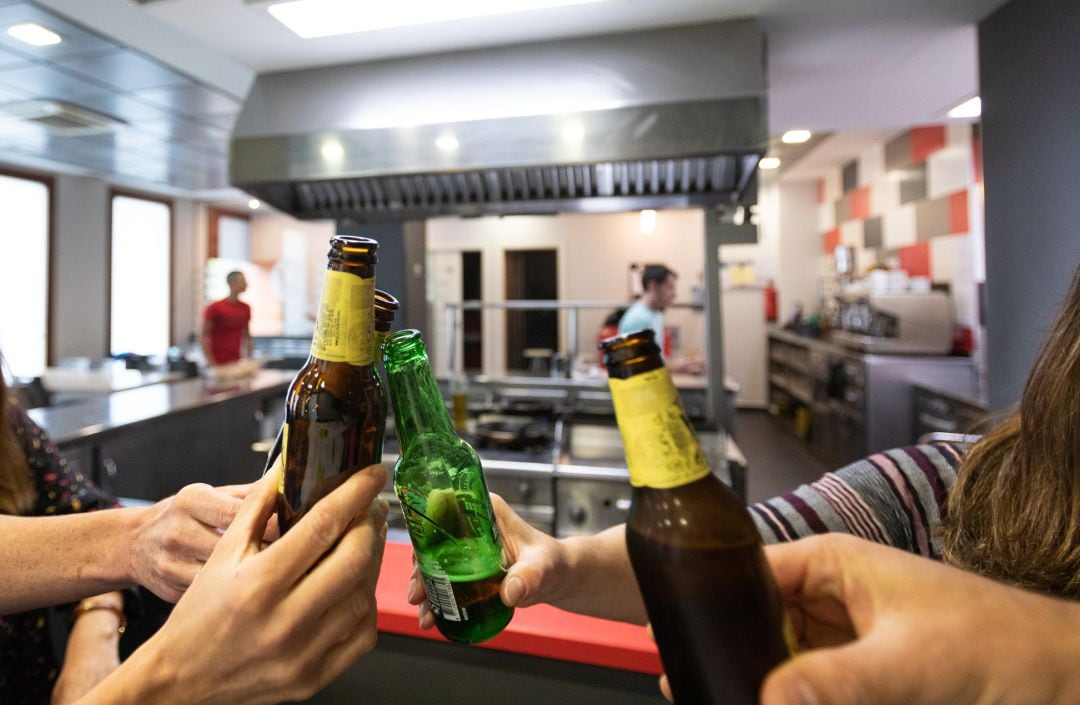 Varias personas brindan con botellas de cerveza en la sociedad gastronómica Larragorri en Vitoria-Gasteiz.