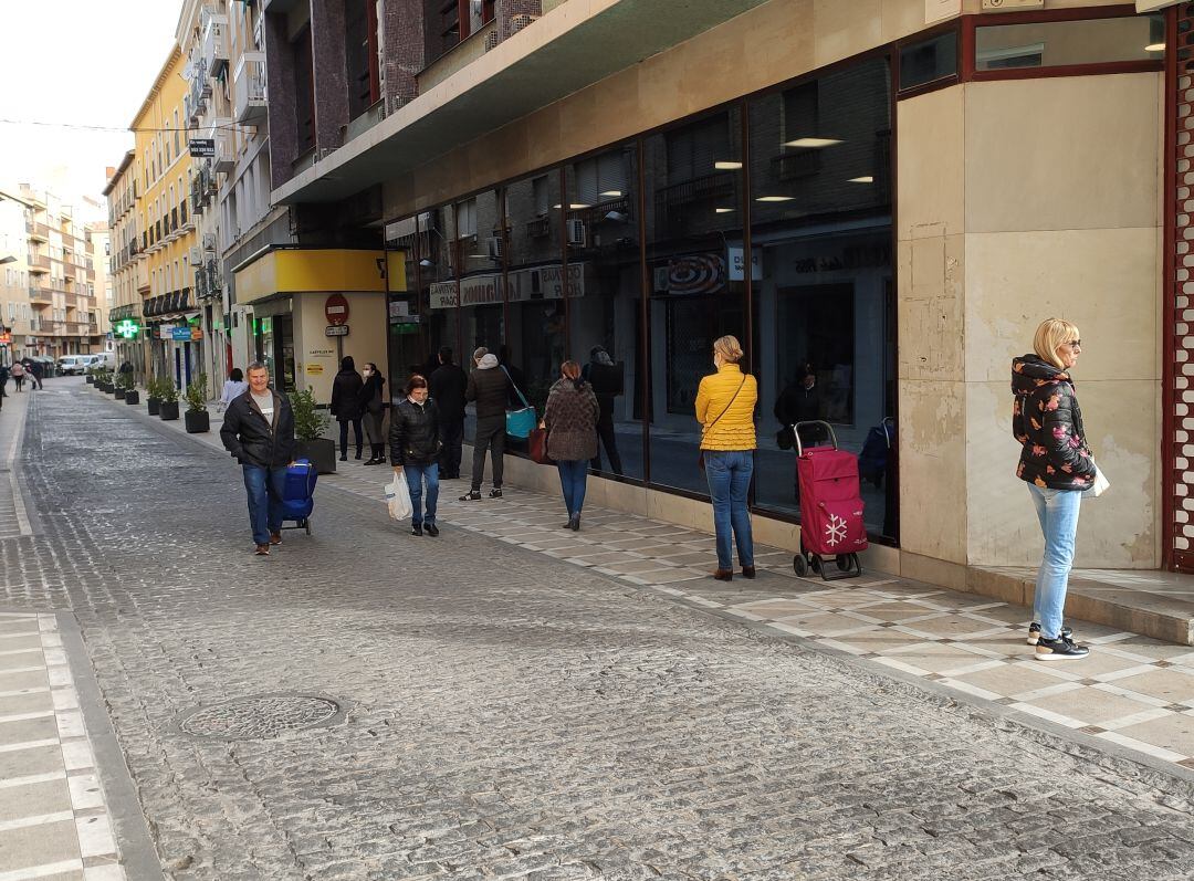 Varias personas esperando, guardando la distancia de seguridad decretada por el Estado de Alarma, para entrar en un supermercado.
