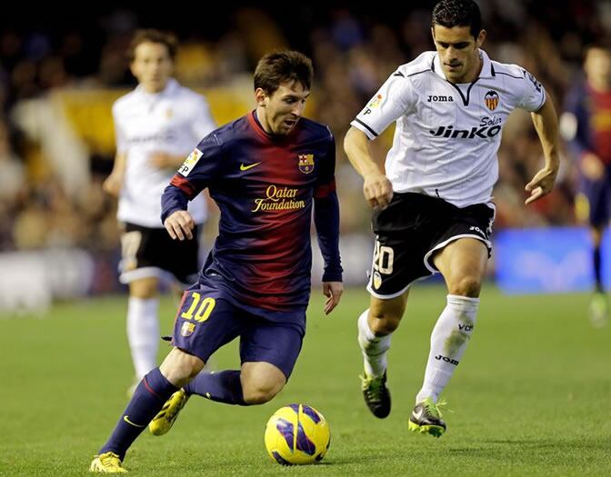 Leo Messi controla el balón ante el defensa portugués del Valencia Ricardo Costa