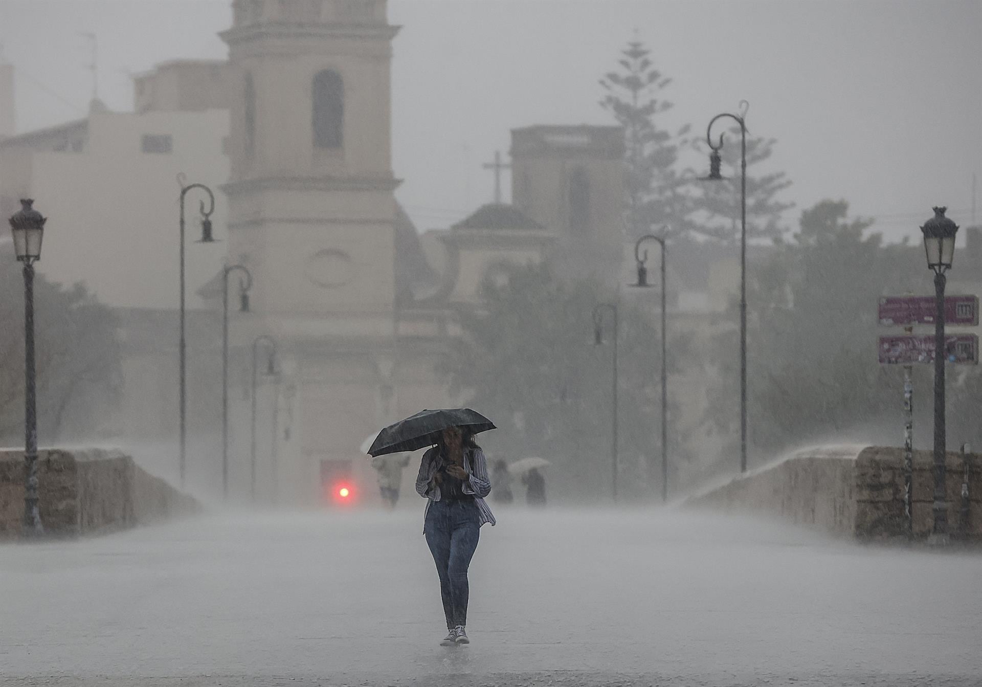 Una persona camina con un paraguas bajo la lluvia en València
