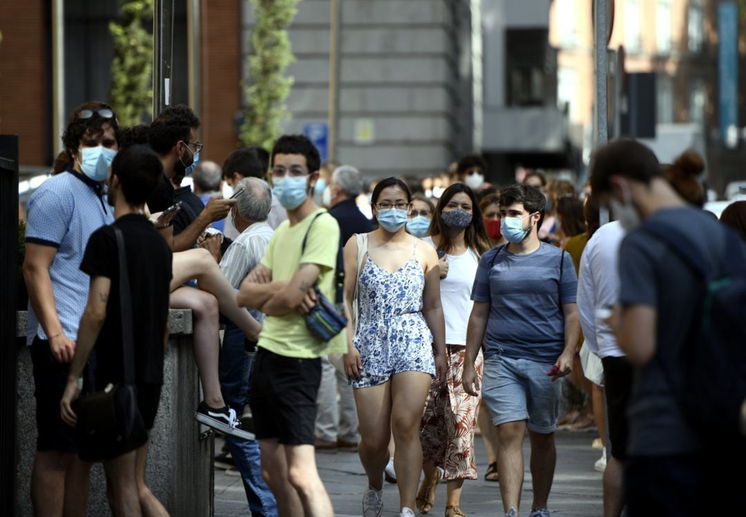 Varias personas caminan con mascarilla por una calle.