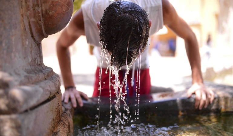 GRA434. CÓRDOBA, 08/07/2015. Un joven se refresca en una fuente del Patio de los Naranjos de la Mezquita Catedral de Córdoba, hoy cuando se mantiene activado en Andalucía el aviso naranja (riesgo importante) por temperaturas que oscilarán entre los 36 y l