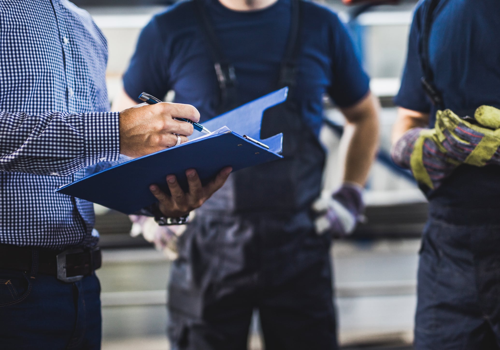 Un hombre señala en los documentos de su carpeta durante una inspección de trabajo junto a operarios