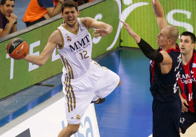 El ala-pívot del Real Madrid Nikola Mirotic intenta dar un pase ante la oposición del pívot polaco del Caja Laboral Maciej Lampe, el 31 de mayo de 2012, durante el cuarto partido de las semifinales de la Liga ACB de baloncesto que se disputa en el pabelló