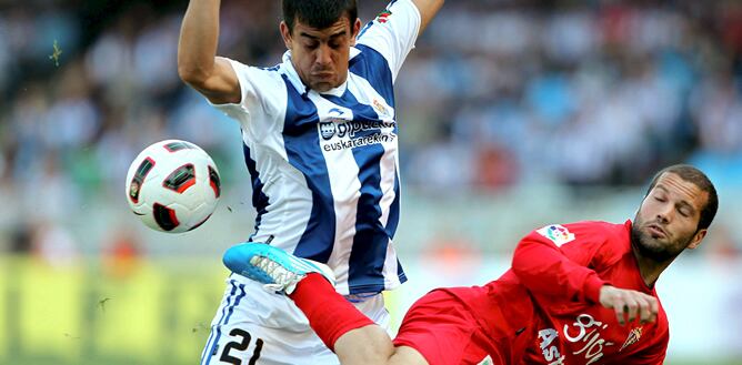 El delantero uruguayo de la Real Sociedad Diego Ifrán lucha por un balón con el defensa del Sporting de Gijón Alberto Lora durante el partido correspondiente a la trigésima segunda jornada del Campeonato Nacional de Liga de Primera División que enfrenta a