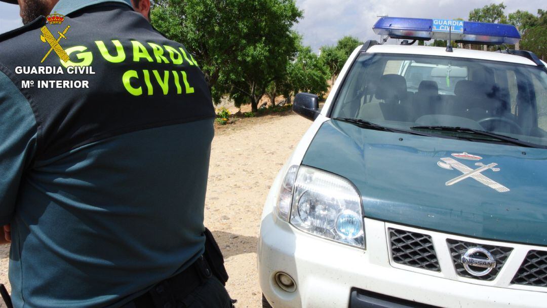 Agente de la Guardia Civil junto a su vehículo.