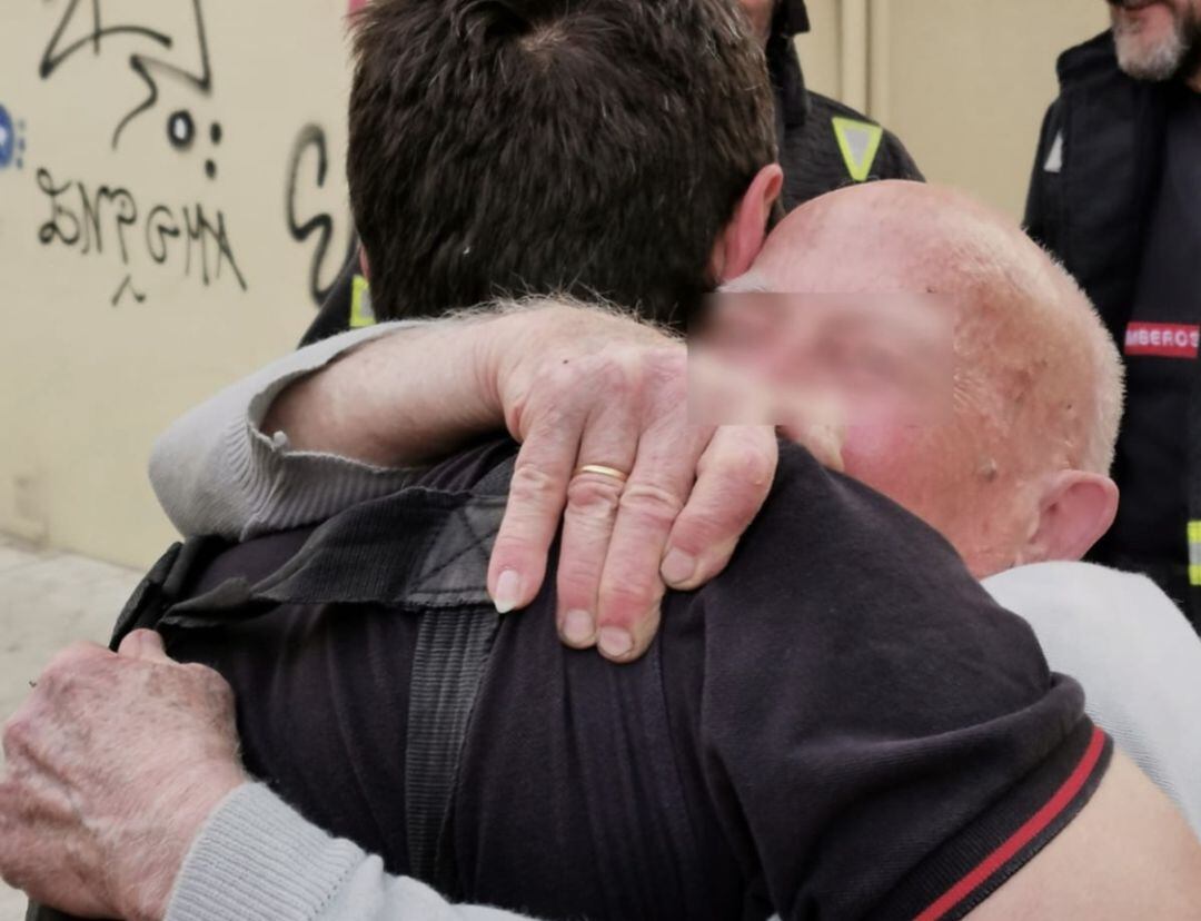 El hombre, de 90 años, abrazado a uno de los bomberos de Málaga