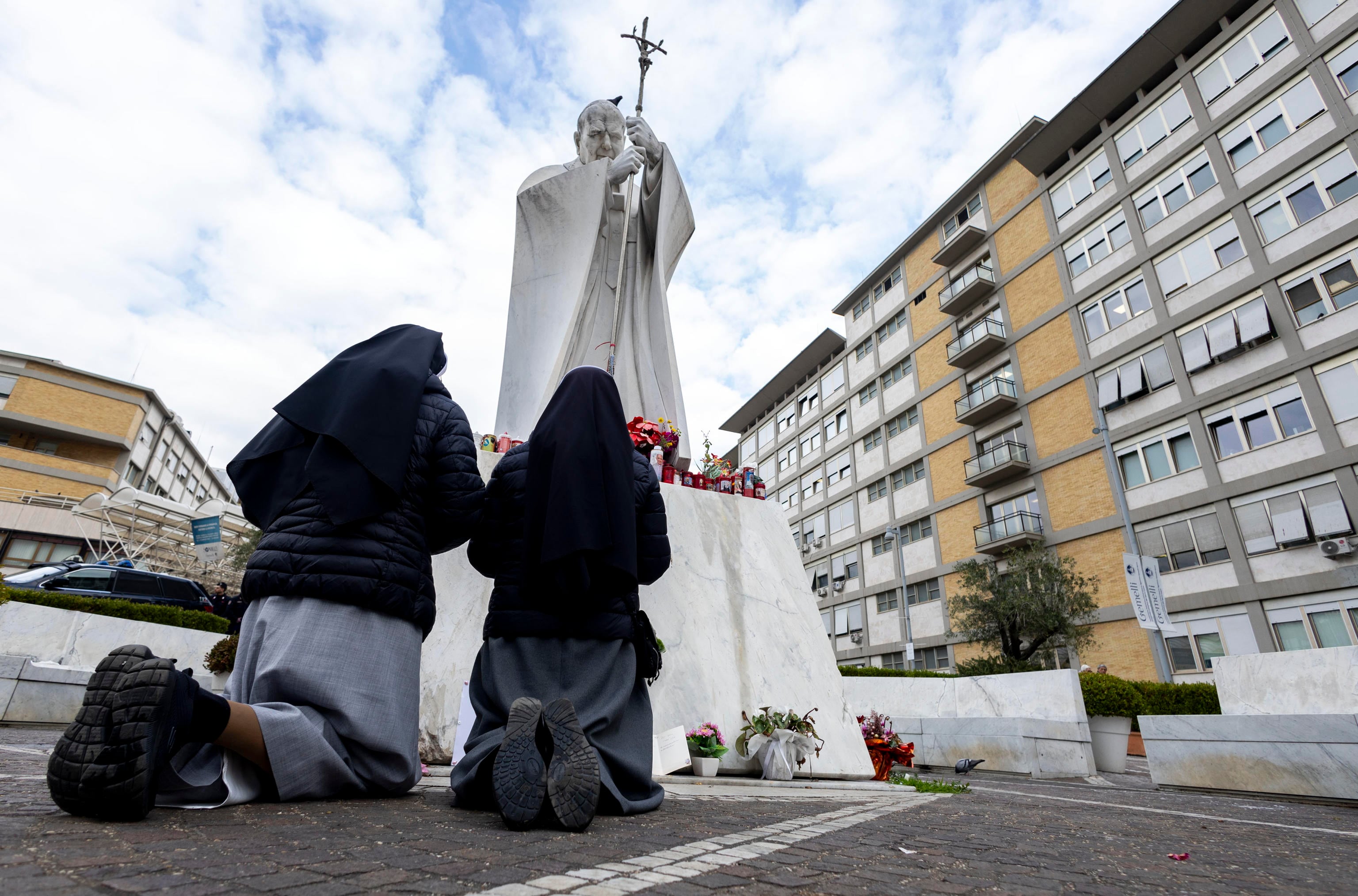 Dos monjas rezan por la salud del Papa Francisco ante la estatua del papa Juan Pablo II