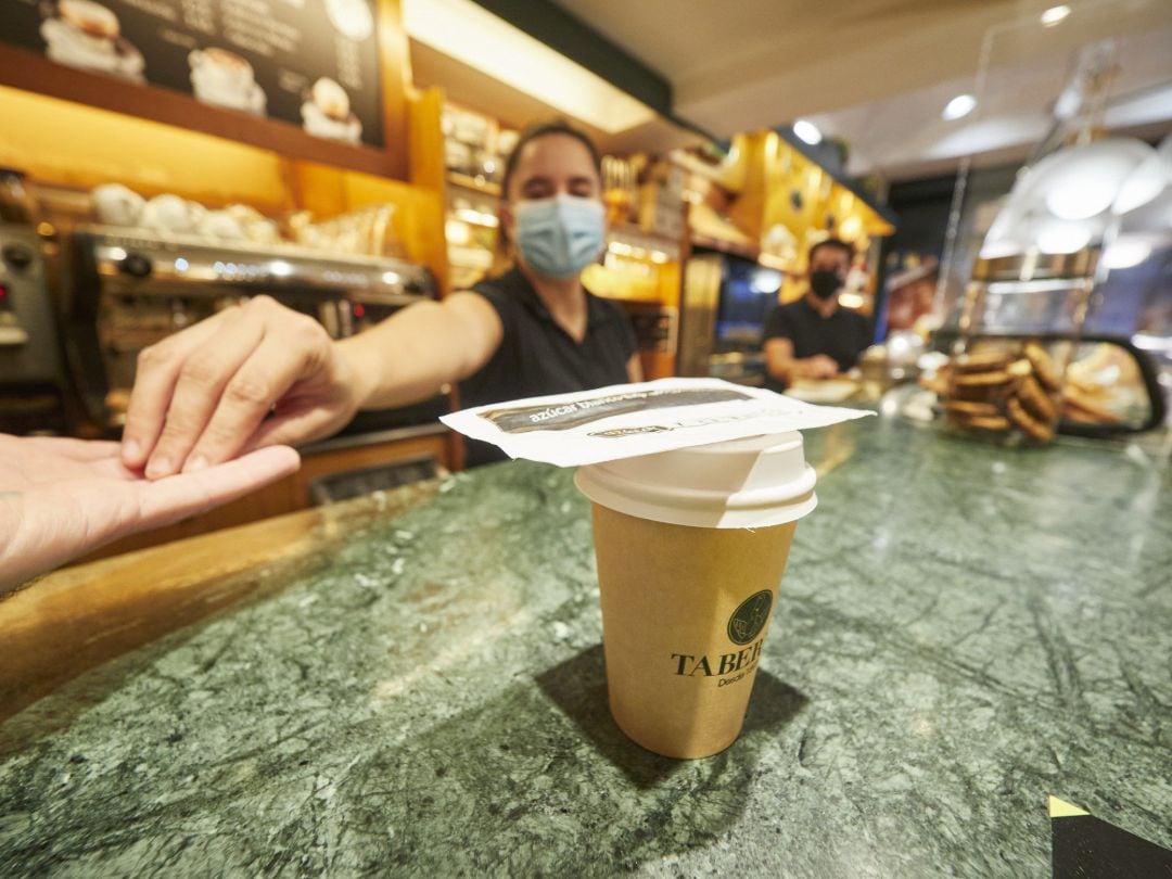 Una camamera entrega el cambio en una cafetería de Pamplona.
