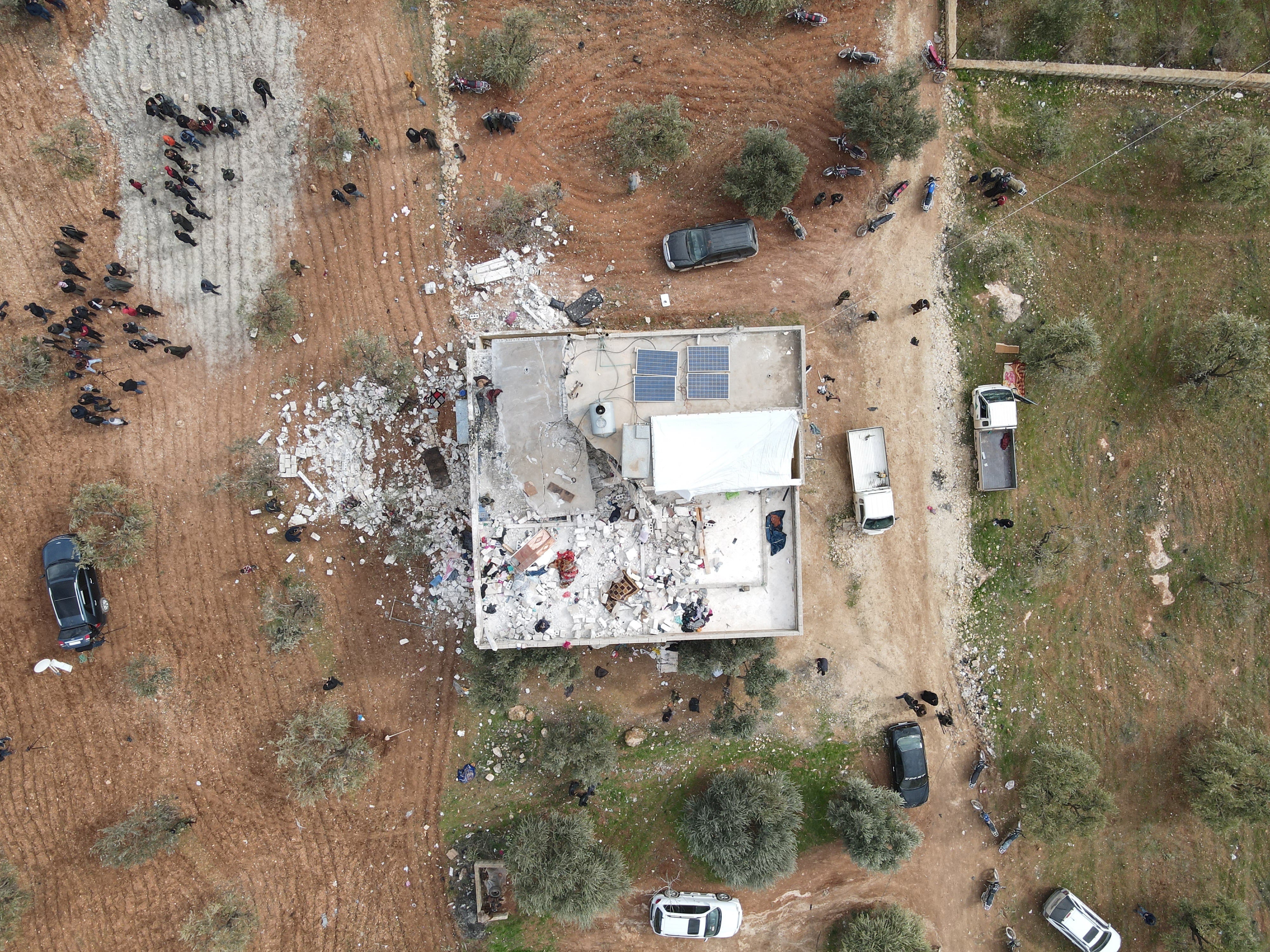 Una fotografía aérea tomada por un dron muestra a personas inspeccionando un edificio dañado después de una supuesta operación antiterrorista de las fuerzas especiales de EEUU en la madrugada en la aldea de Atma en el campo norte de Idlib, Siria