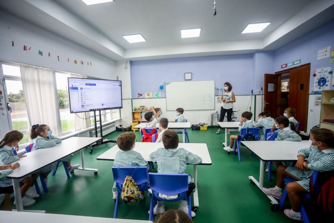 Archivo - Varios niños escuchan las explicaciones de su profesora en una clase de un colegio 