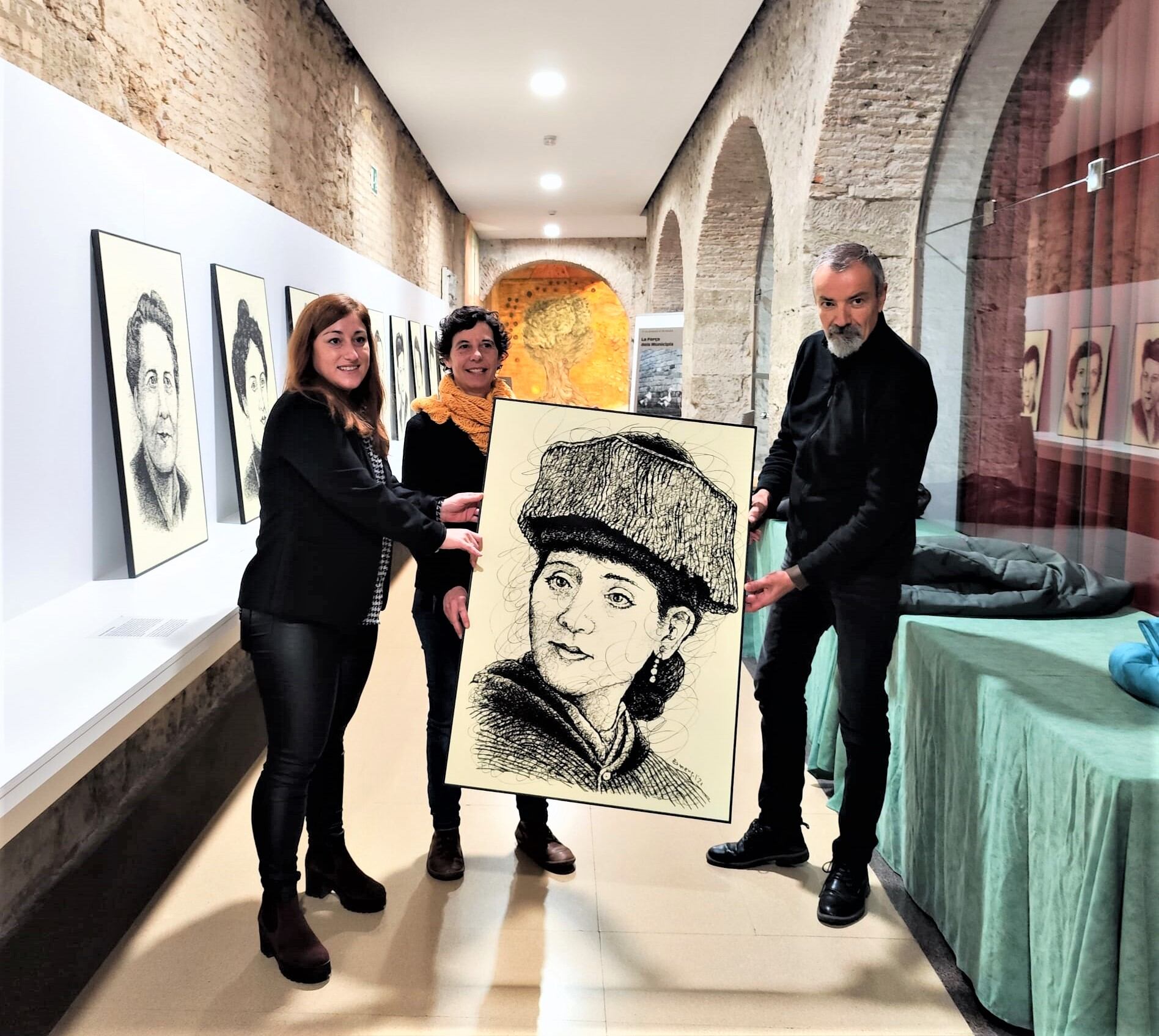Moment del desmuntatge de l'exposició "Les dones que donen nom a Lleida", que ara es veurà a Maldà. A la foto, amb el retrat de Martina Castells, juntament amb l'artista, Paco Ermengol, l'alcaldessa de Maldà i la diputada Helena Martínez.