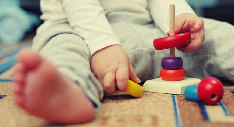 Imagen de un bebé jugando con piezas de madera.