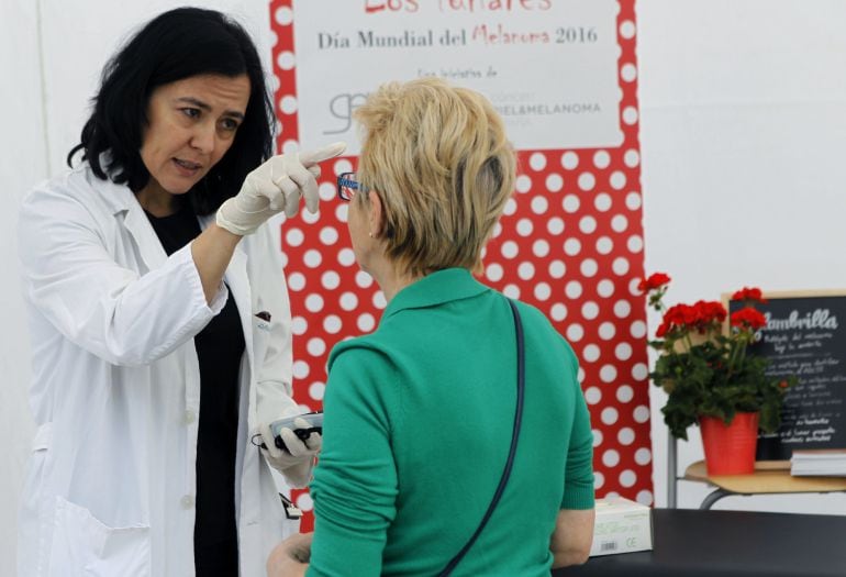 Una médica atiende a una de las personas que ha acudido a la carpa instalada en Madrid por el Grupo Español de Pacientes con Cáncer coincidiendo con el Día Mundial contra el Melanoma. 