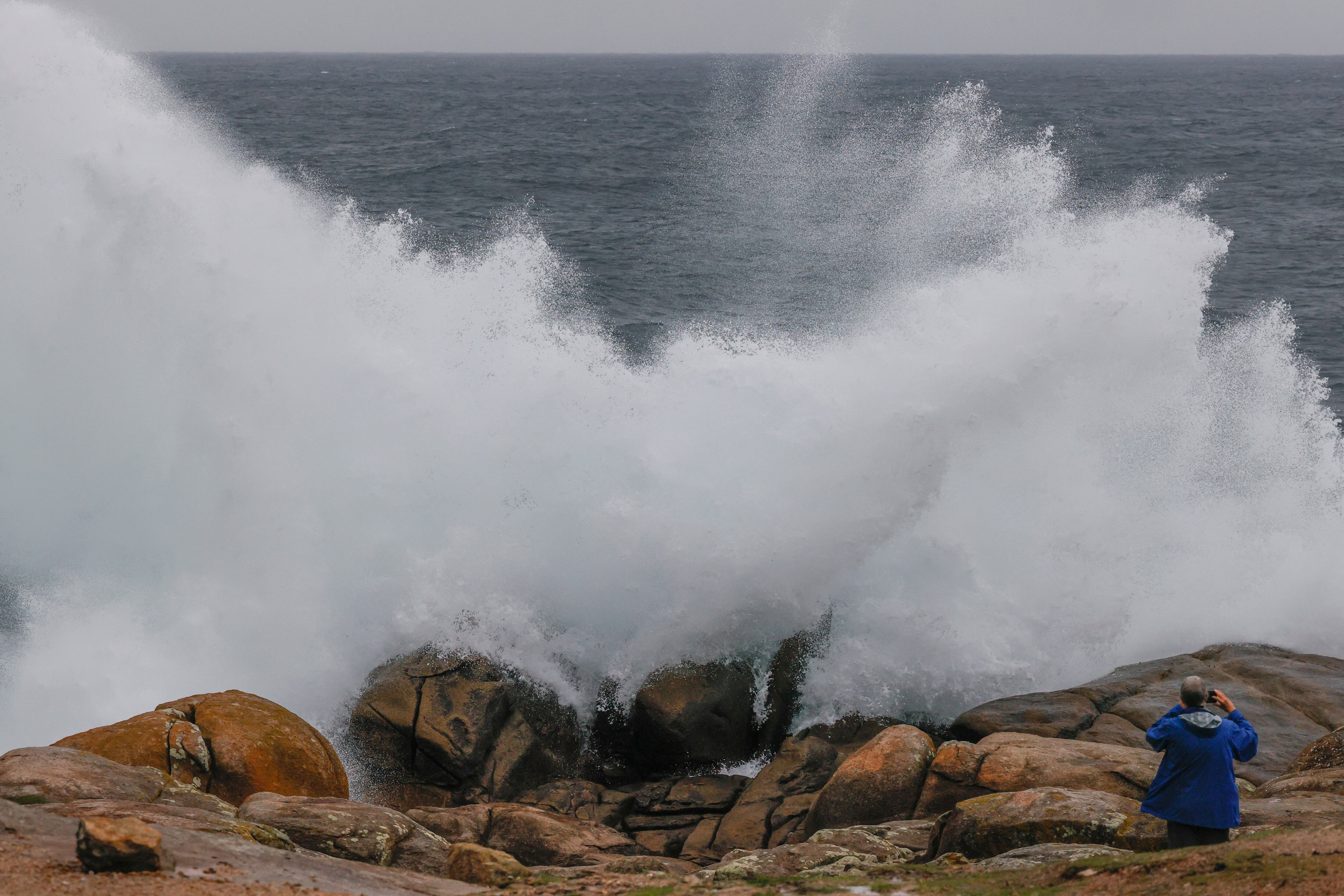 Un turista fotografía las olas en Muxía. L