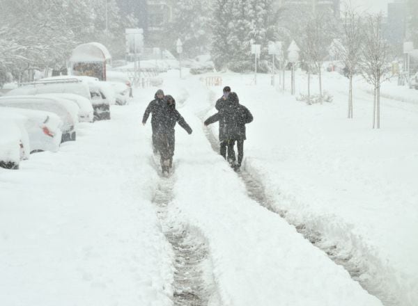 Algunas personas caminan por una calzada completamente cubierta de nieve de una calle en Alcobendas (Madrid) durante la nevada de Filomena