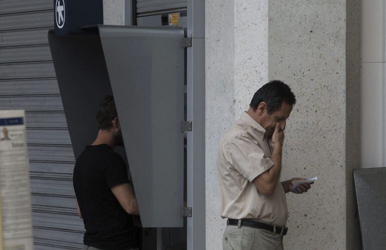 Varias personas sacan dinero de un cajero en Atenas.