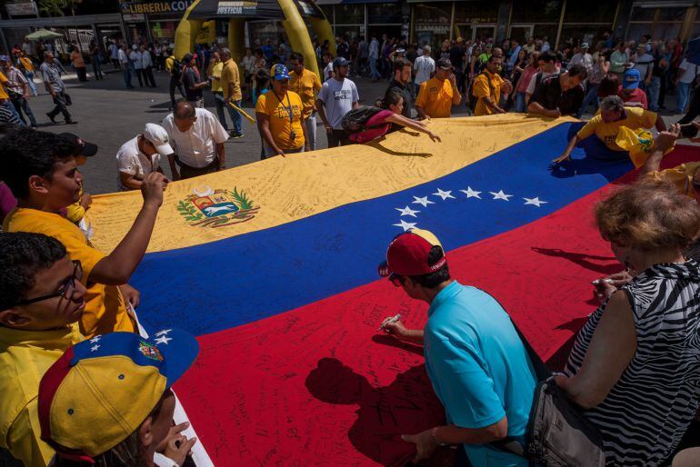 Un hombre firma una bandera venezolana en la ciudad de Caracas