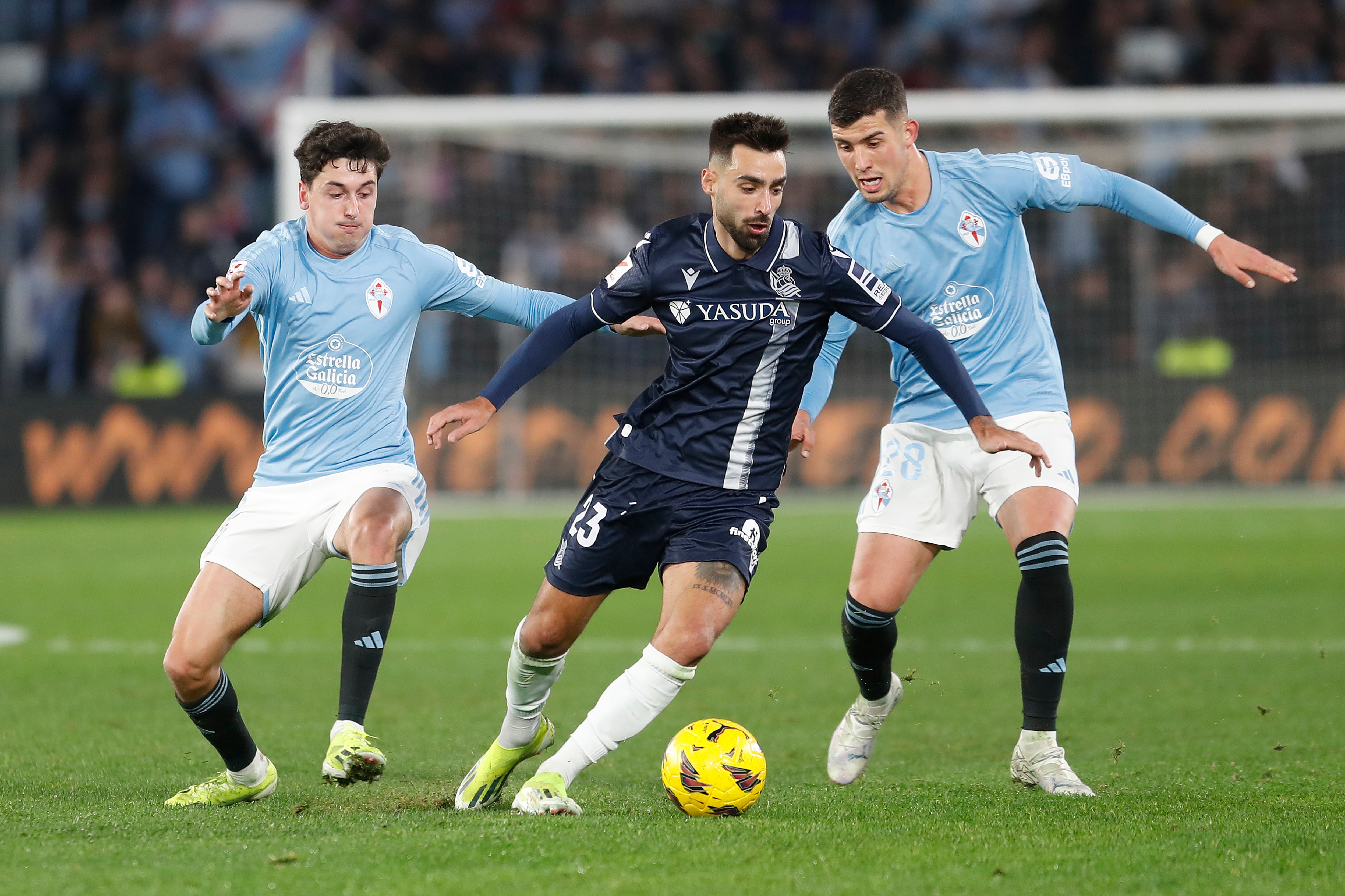 Vigo (Pontevedra) 20/01/2024.- El centrocampista de la Real Sociedad, Brais Méndez (c), controla el balón ante el jugador del Celta, Carlos Domínguez (d), durante el encuentro correspondiente a la jornada 21 de Primera División que disputan hoy sábado Celta y Real Sociedad en el estadio Balaidos, en Vigo. EFE / Salvador Sas.
