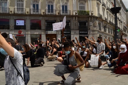 Manifestantes arrodillados y con el puño en alto en solidaridad por las víctimas mortales del racismo, en la Puerta del Sol.