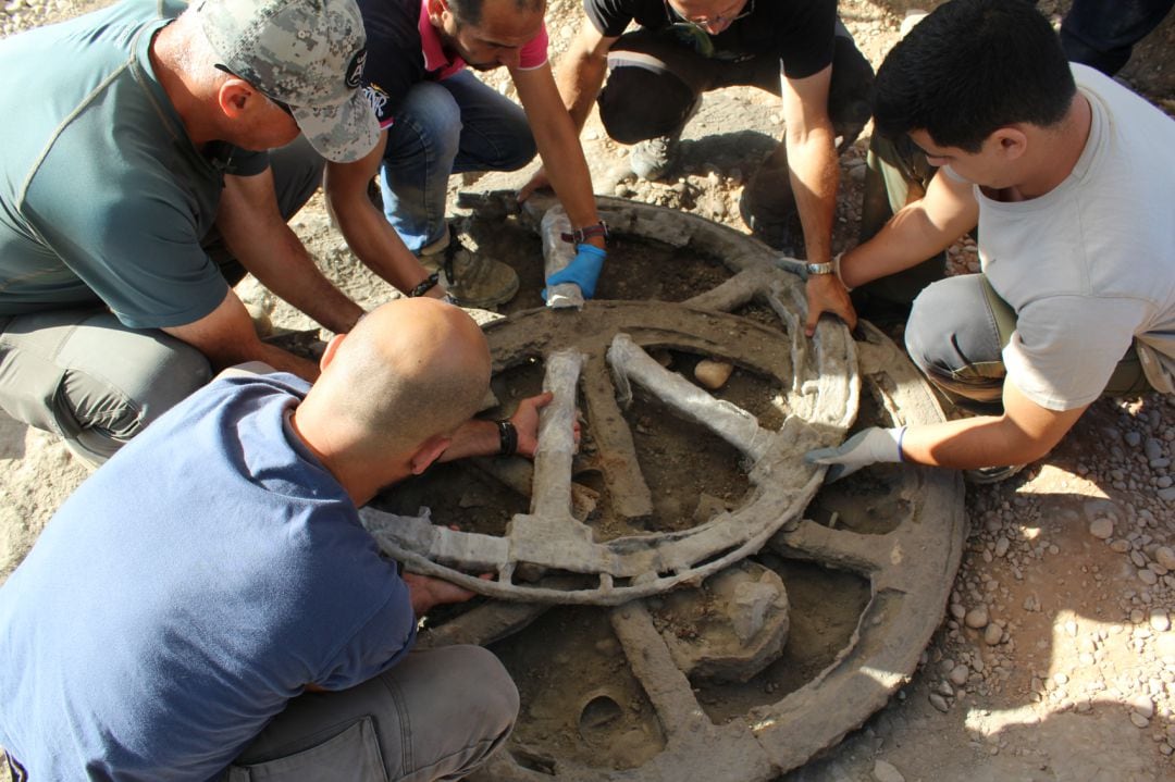 Miembros del equipo de la excavación extraen una de las ruedas del carro.