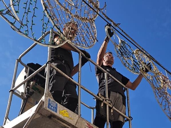 Operarios trabajan en la instalación de las luces de Navidad en Tavernes de la Valldigna.