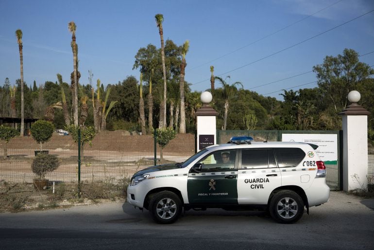 Un coche de la Guardia Civil espera frente a la entrada del campo de golf La Dama de Noche, registrada durante la operación