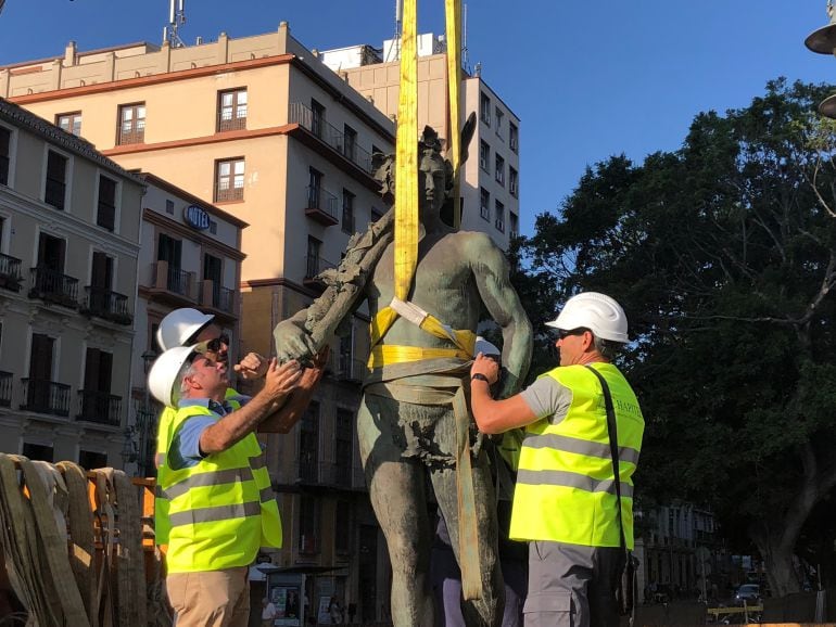 Operarios retirando la escultura &quot;Alegoría al trabajo&quot;.