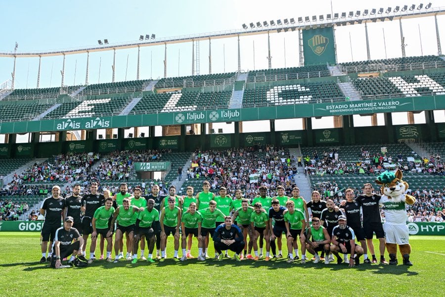 La foto de familia tras el entrenamiento con los escolares al fondo