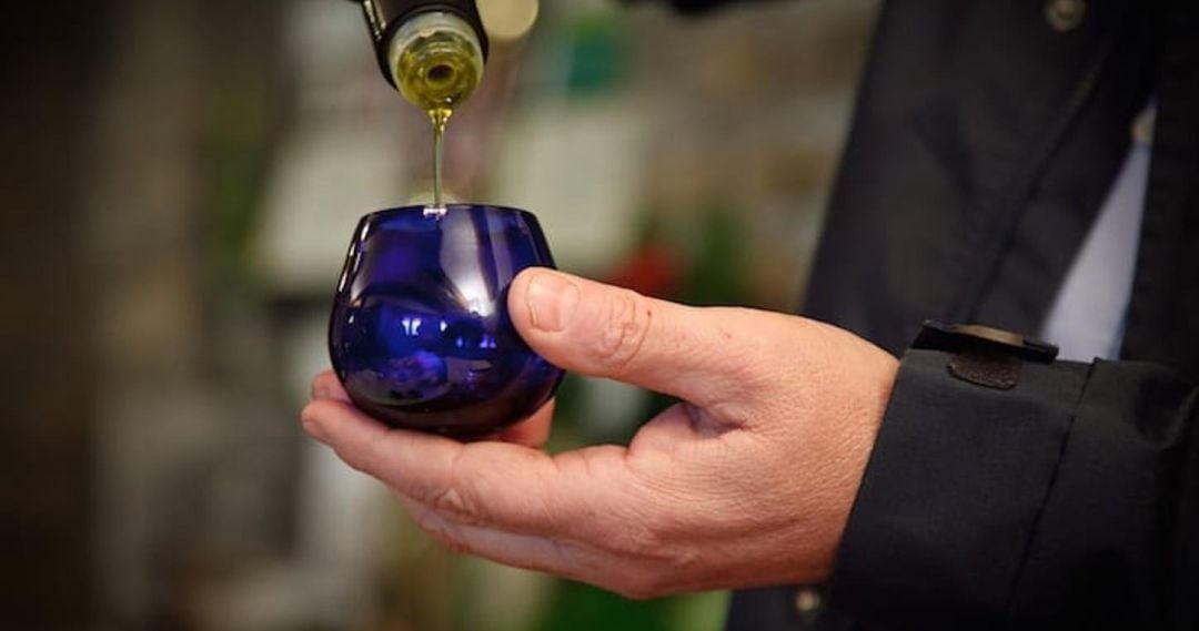 Un hombre echa aceite de oliva en un vaso de cata.